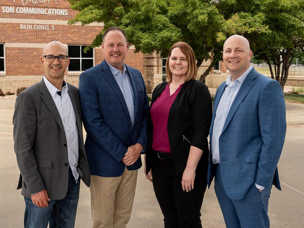 The SDN Communications executive team of Ryan Dutton, Ryan Punt, Sarah Tuntland and Jake VanDewater pose for a photo outside of the SDN building