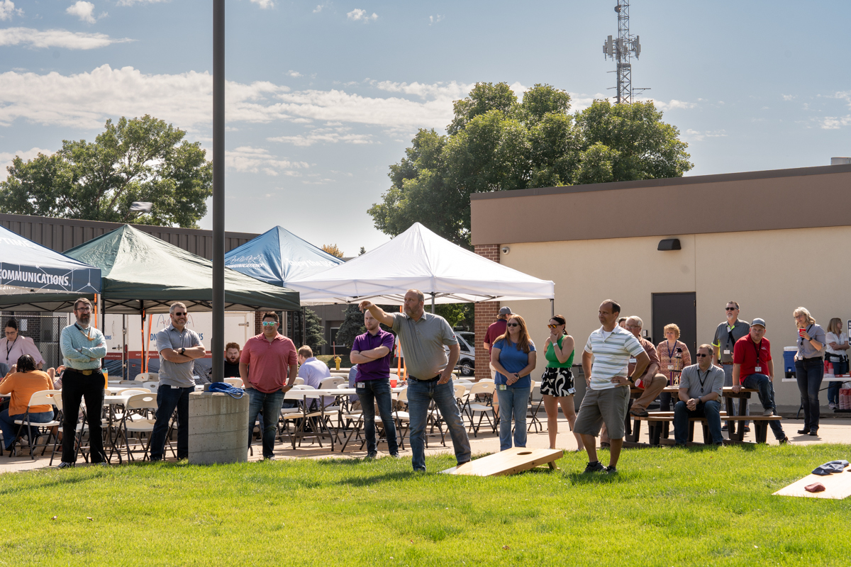 SDN employees stand around cornhole boards and gather to talk at a team event.