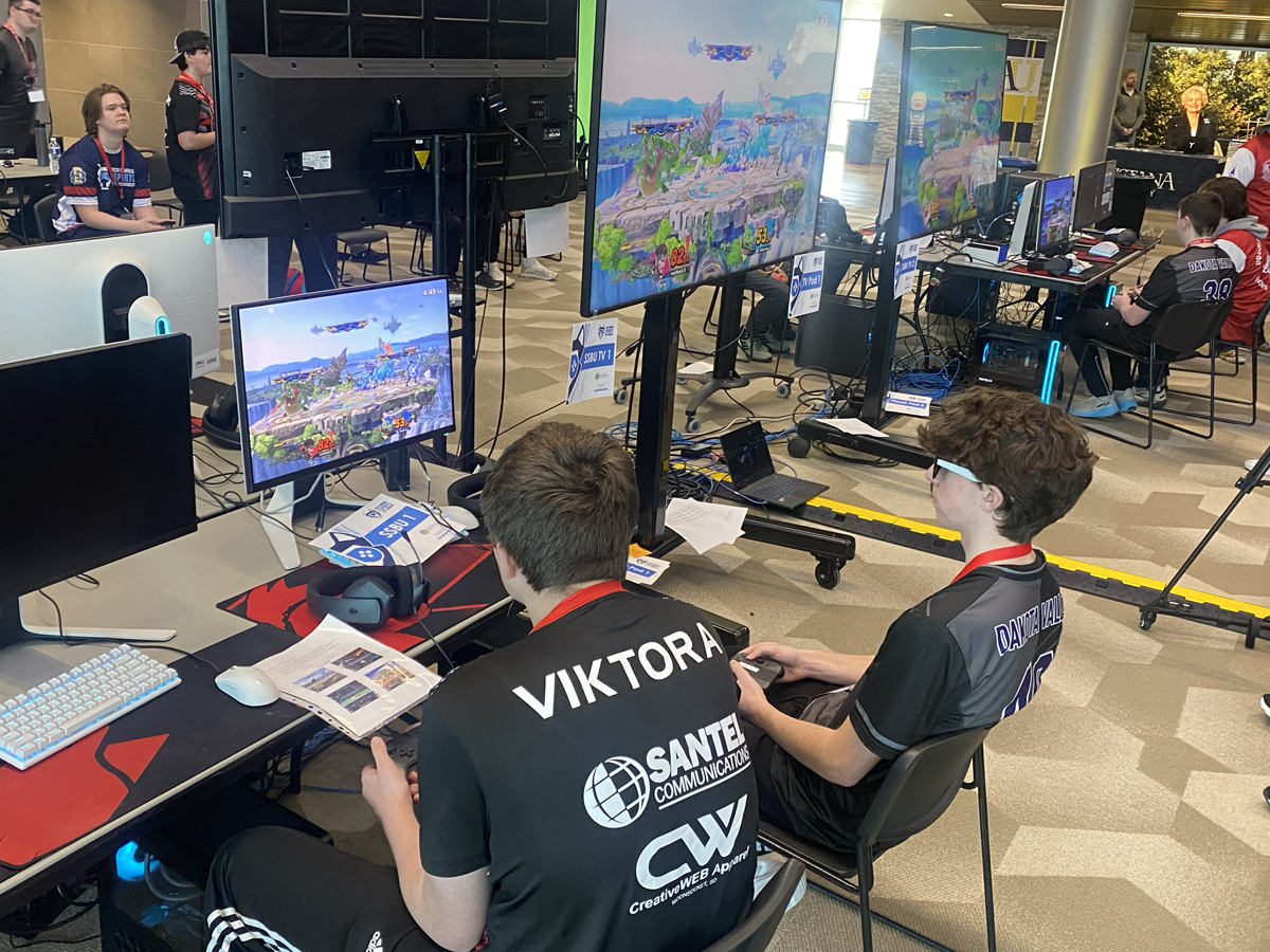 Two high school boys sit in front of a monitor and play video games at an esports state tournament.