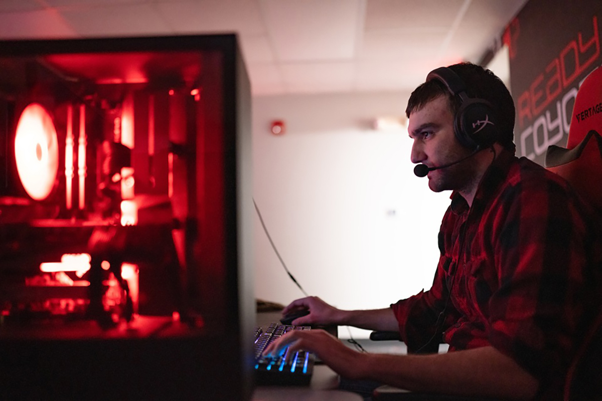 A University of South Dakota esports player sits in front of a computer and plays video game