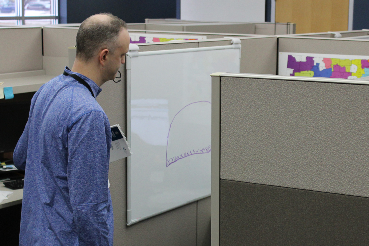 Chaplain talking with employee in cubicle