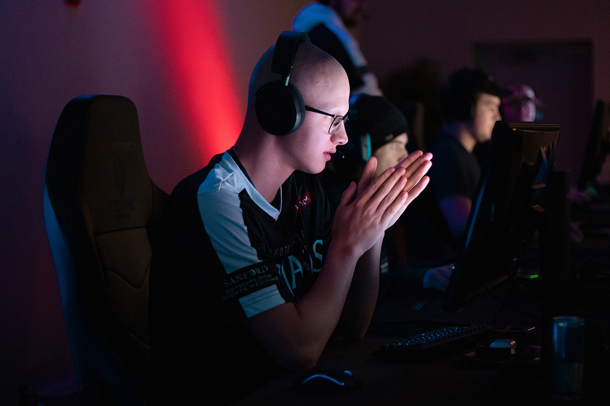 A Dakota State University esports player sits in front of a computer with his elbows at the desk.