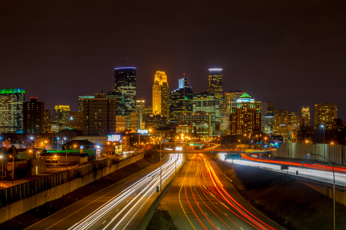 downtown minneapolis skyline at night with streams of light from tail lights on the interstate