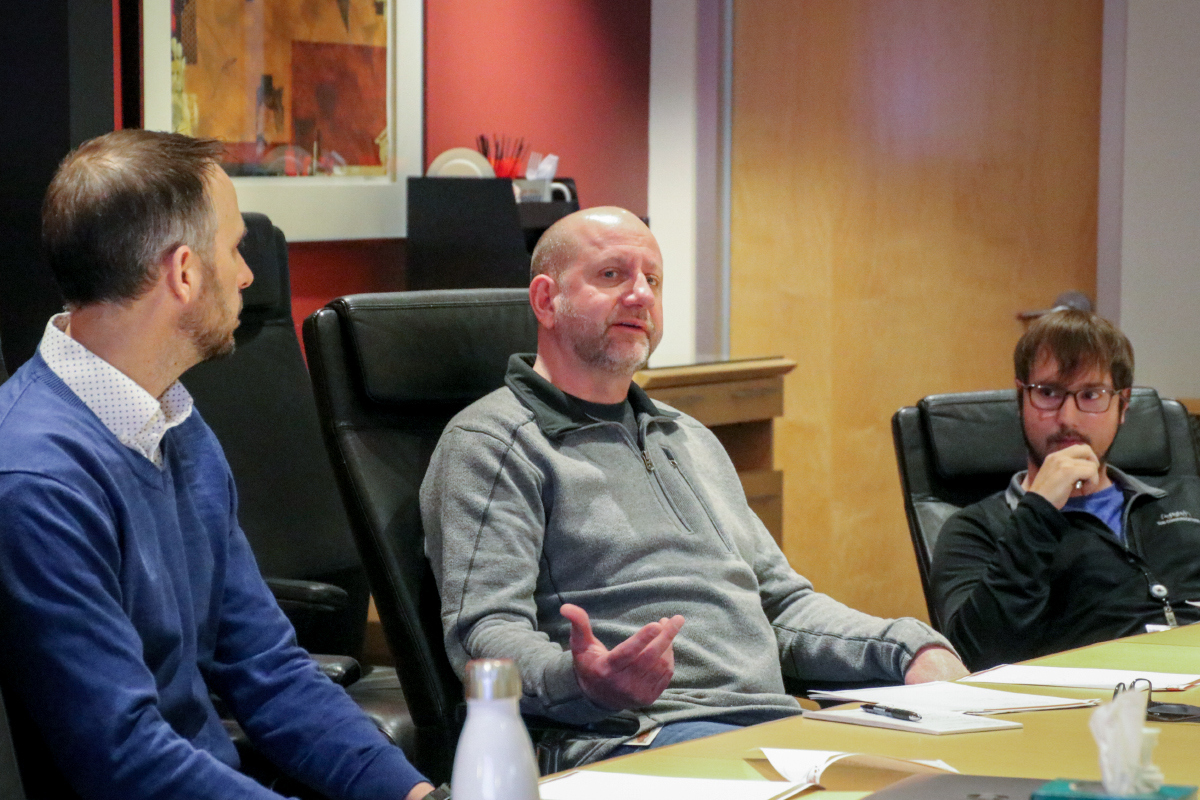 Three employees in discussions at board room table