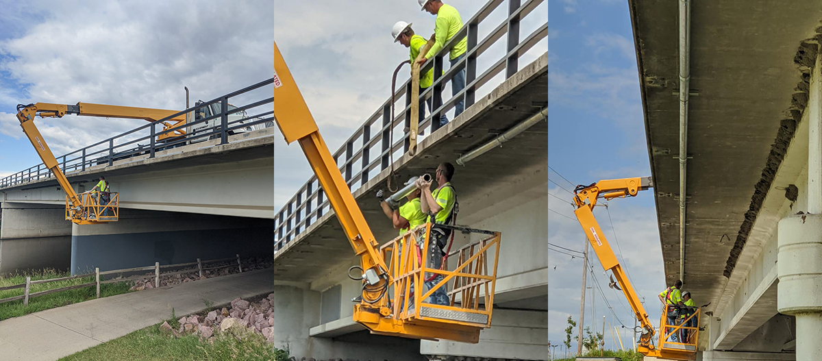 Crews using snooper to install conduit underneath bridge over Big Sioux River