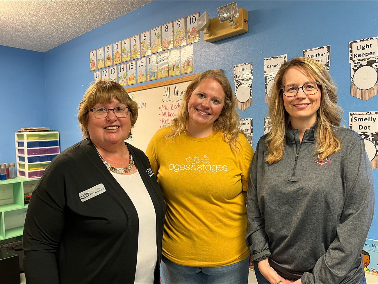 Three women pose for a photo in a classroom.