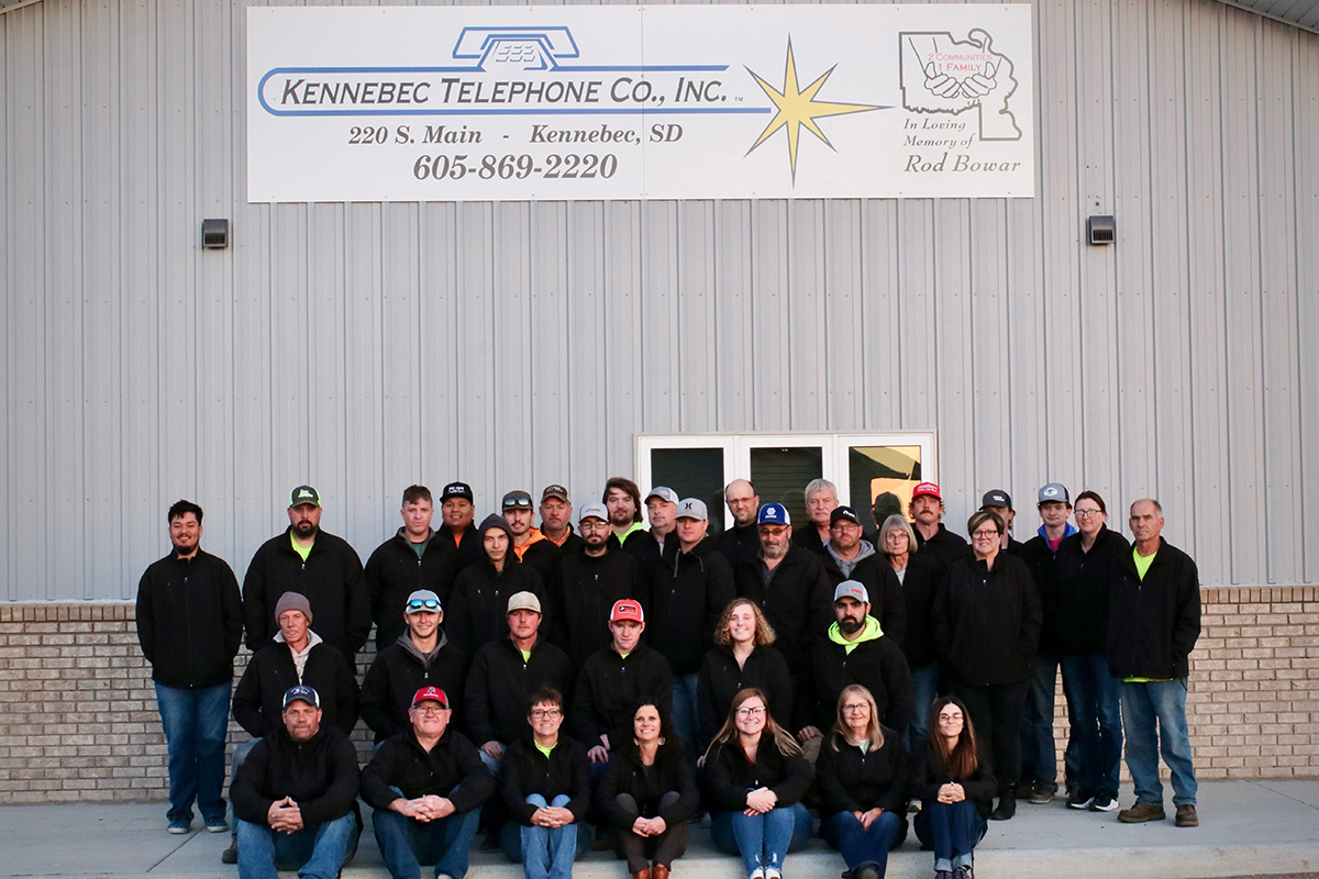 A group of about 30 Kennebec Telephone Co. employees pose for a group photo in front of the company's building