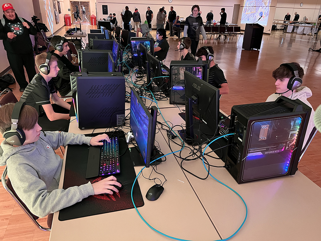 Students play video games in a room filled with monitors.