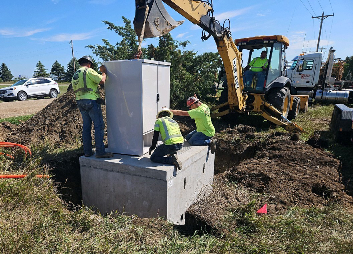 Construction workers install fiber internet in a ditch.