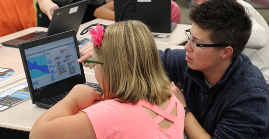 Lowell elementary student reviewing coding project with SDN employee, Brittany