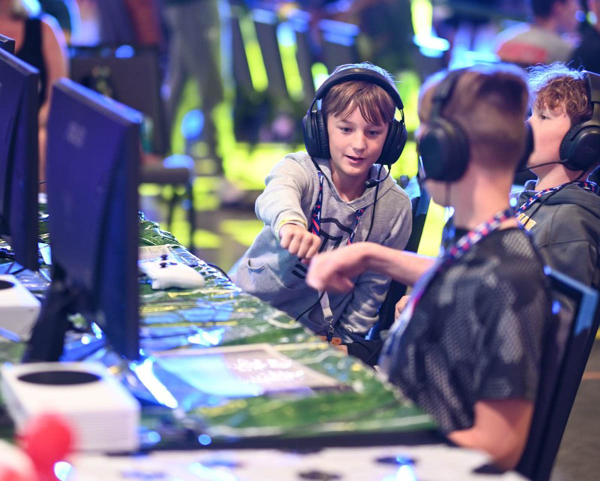 A group of three kids playing video games at an esports tournament give each other a fist bump