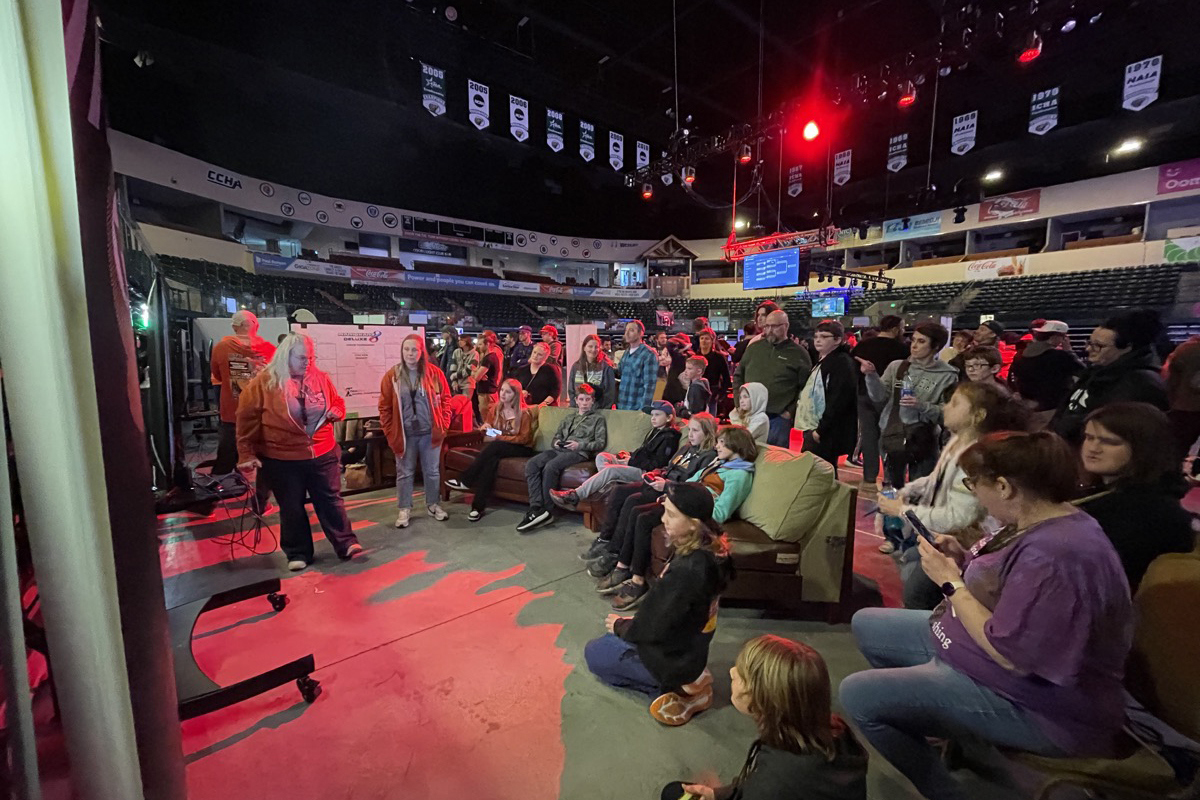 Participants compete in "Mario Kart 8 Deluxe" while sitting on couches at GigaZone in Bemidji, Minnesota, as spectators look on.