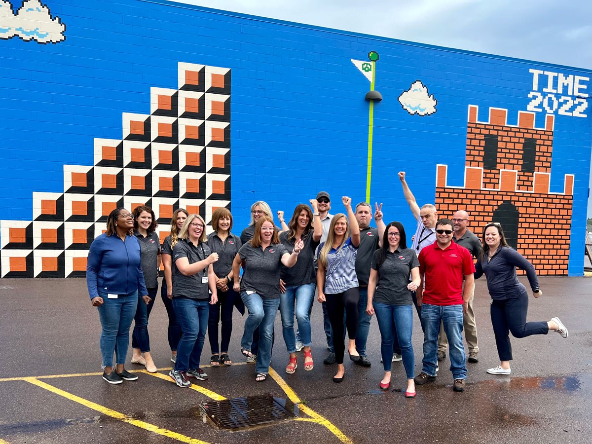 SDN Communications employees stand in front of Mario mural