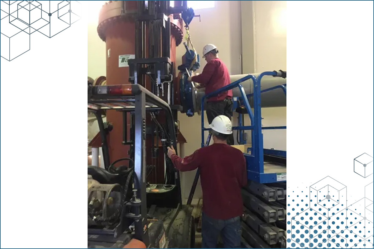 two men in hard hats working on large equipment