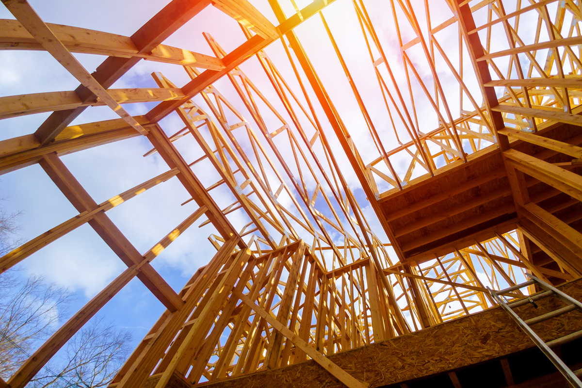 looking up to the sky through trusses of a new home being built