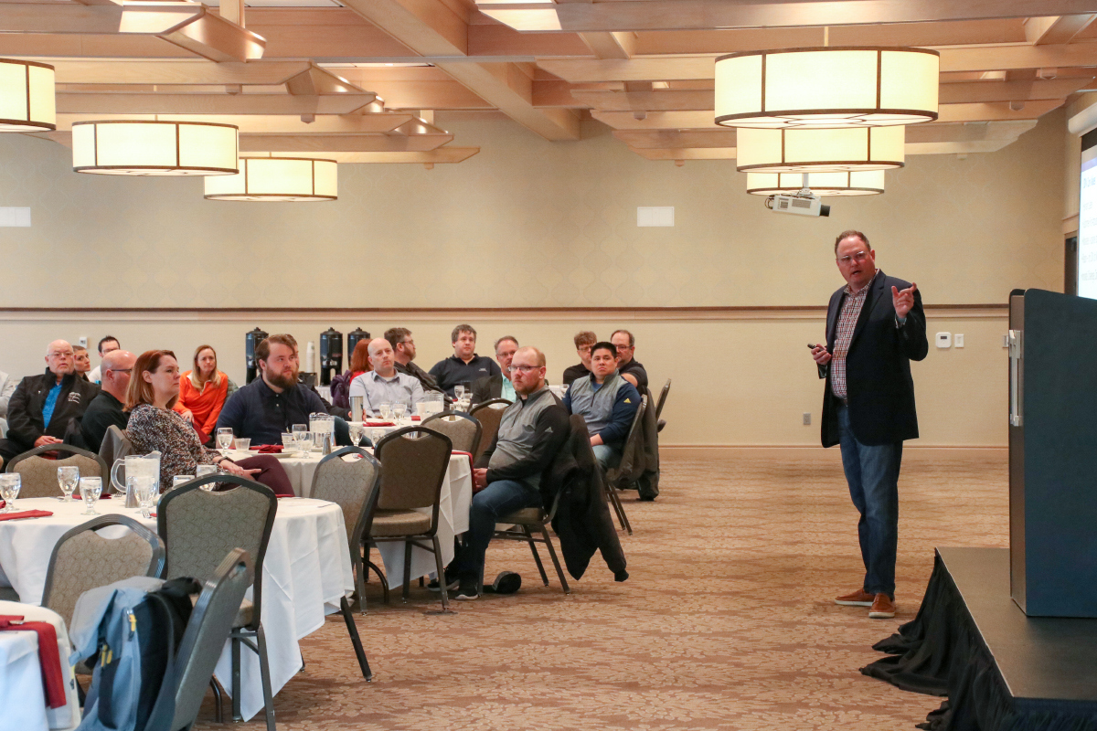 Ryan Punt presenting in front of banquet room full of employees