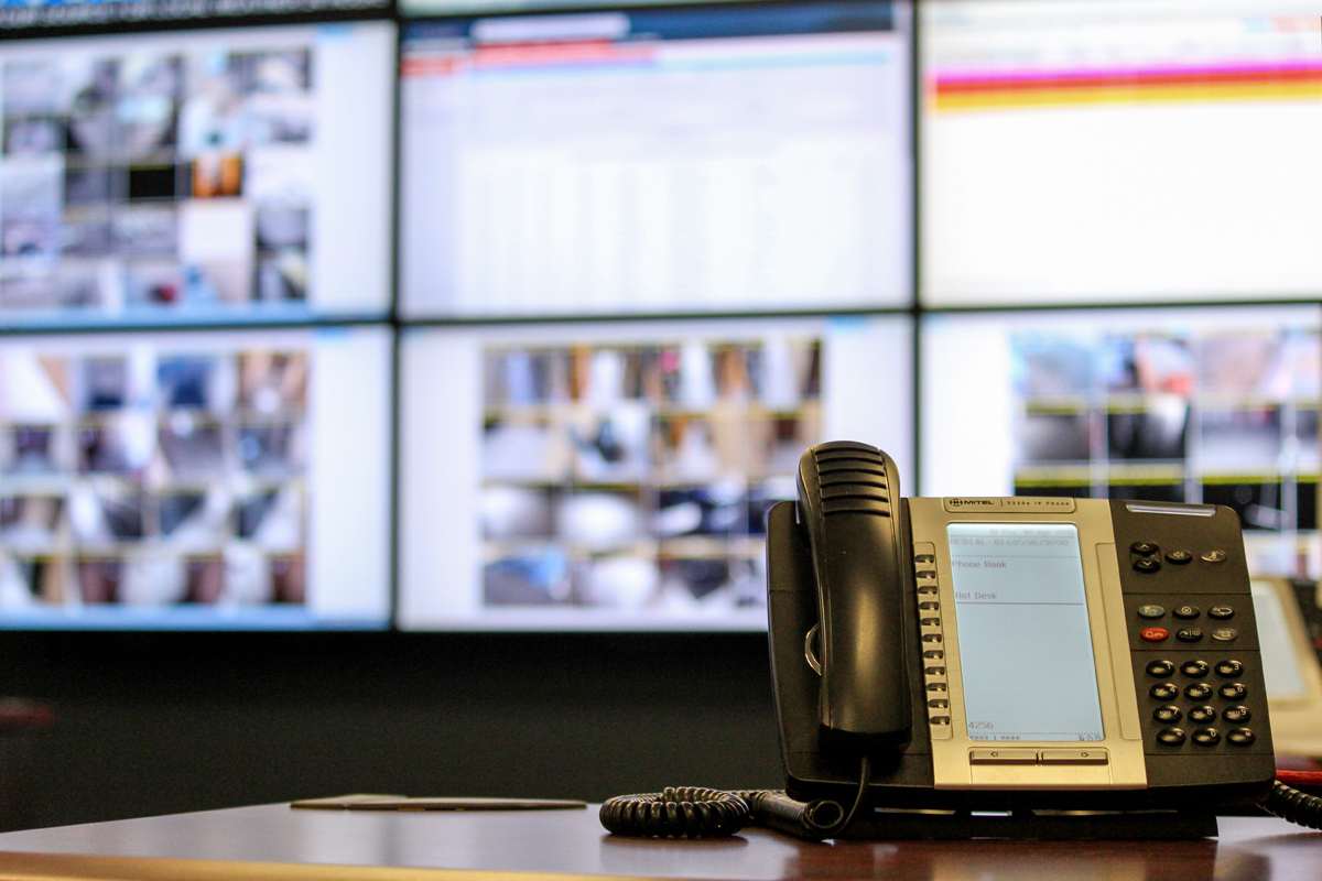 Telephone on a desk with wall of monitors behind it in the NSC