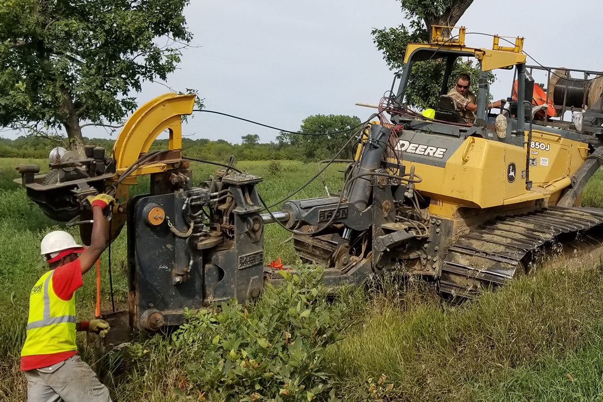 large plow equipment cutting the ground while inserting fiber cables
