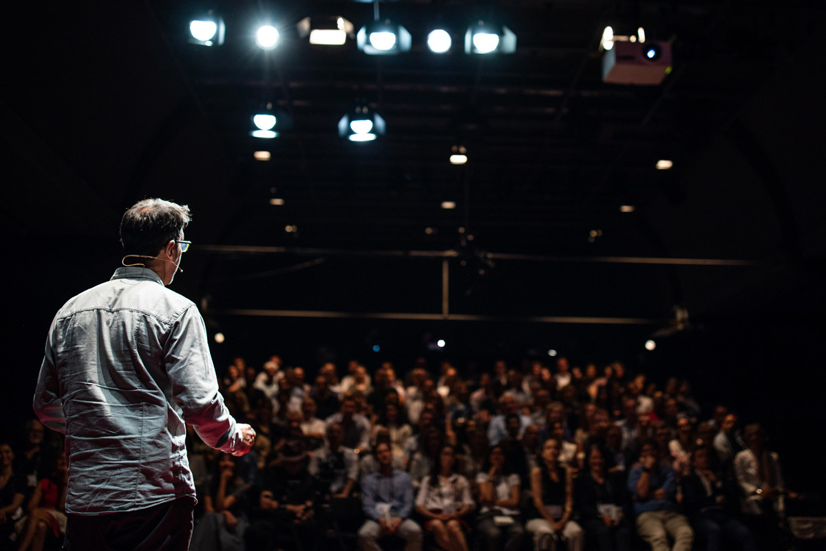 speaker presenting on stage to an audience