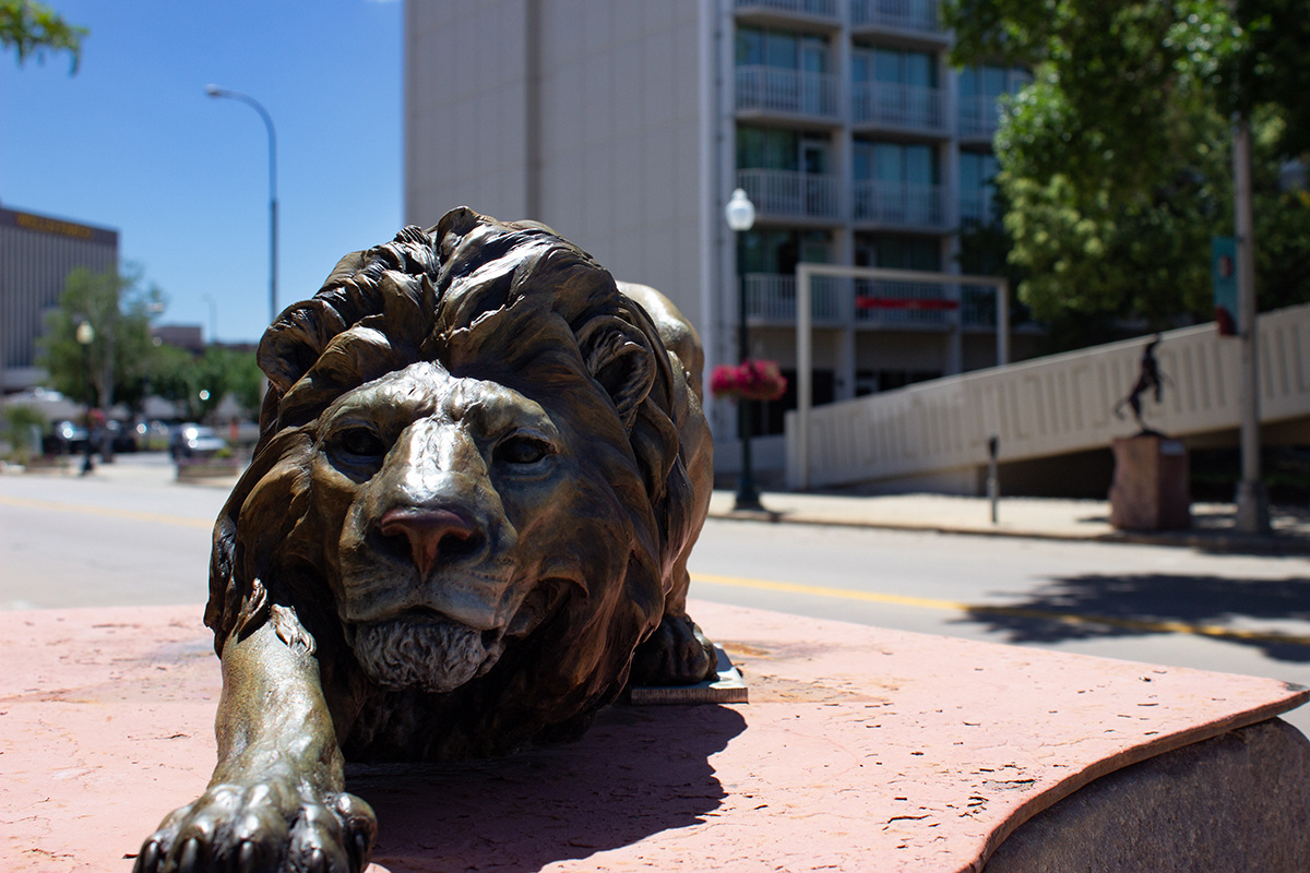 rustic bronze statue of lion crouching and stalking its prey