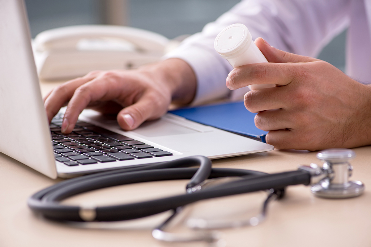 Stock image of a doctor looking at a computer with a stethoscope in the foreground