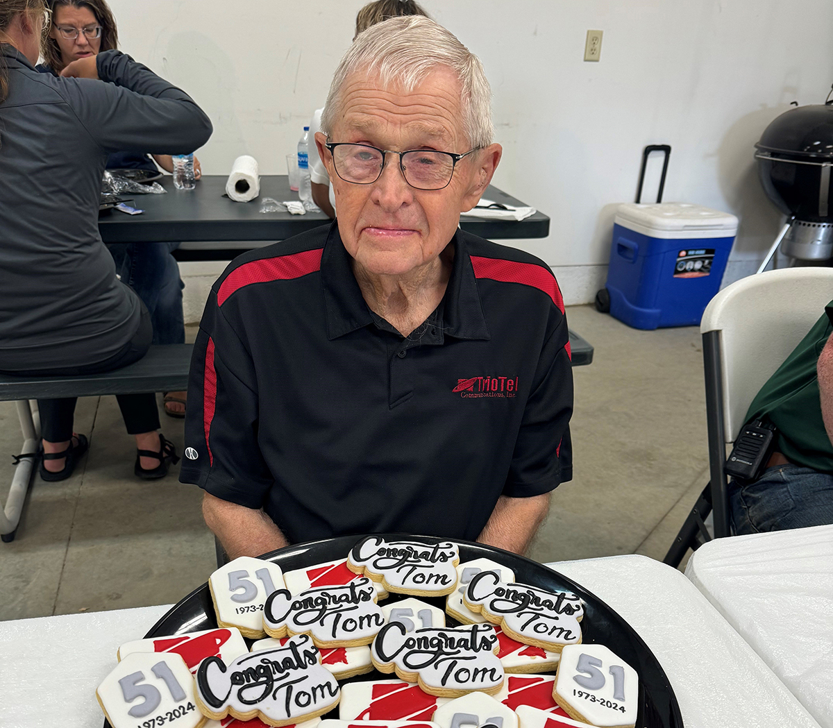 TrioTel Communications Board of Directors member Tom Hueners sits sits in front of a pile of cookies with his name on it during his retirement party.