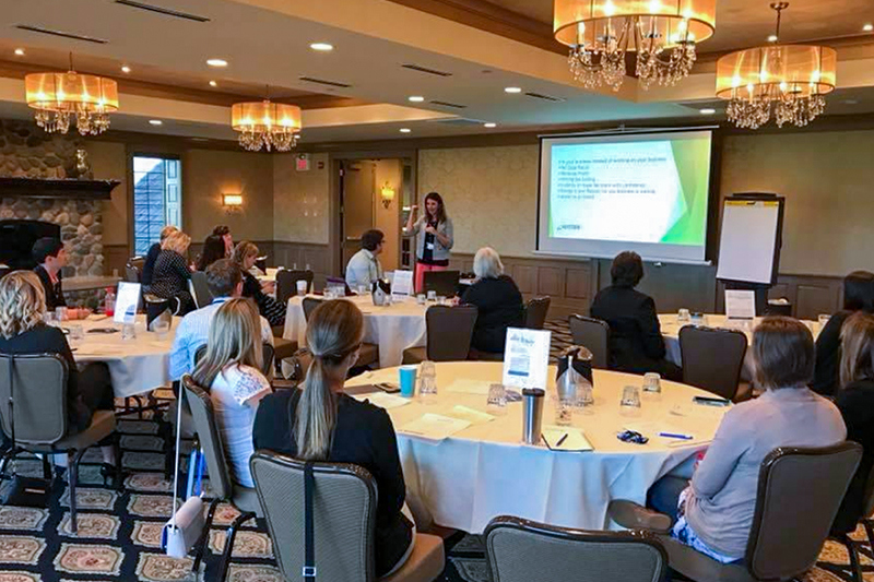 tables of employees focused on presenter in banquet room