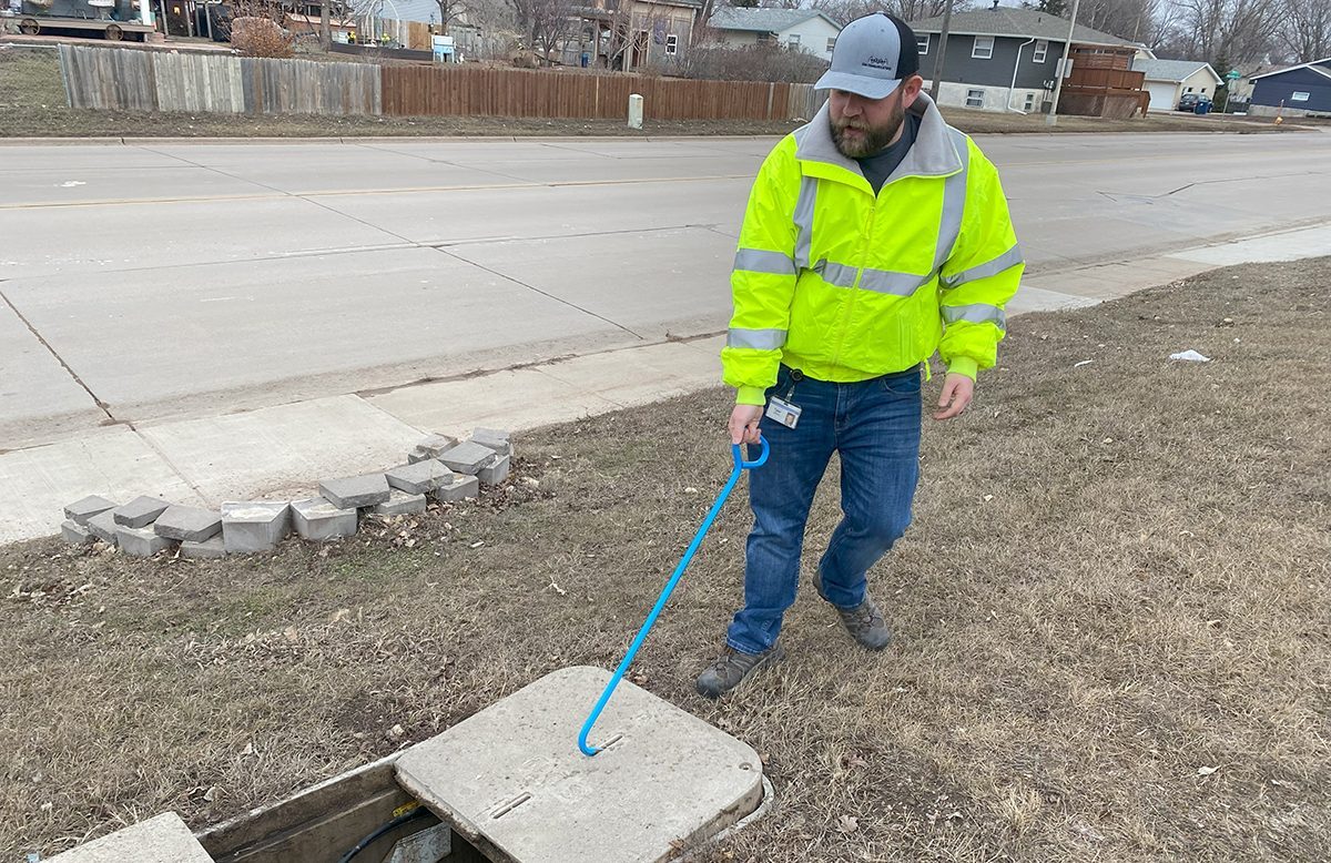 Tyler Larson opens up a cement cover to expose SDN Communications' fiber internet