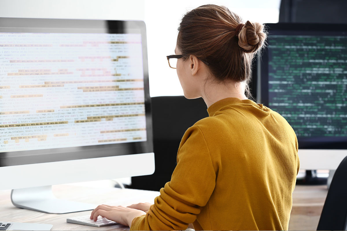 Woman looking at code on computer screen