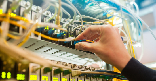 Engineer plugging in connectors to a fiber panel