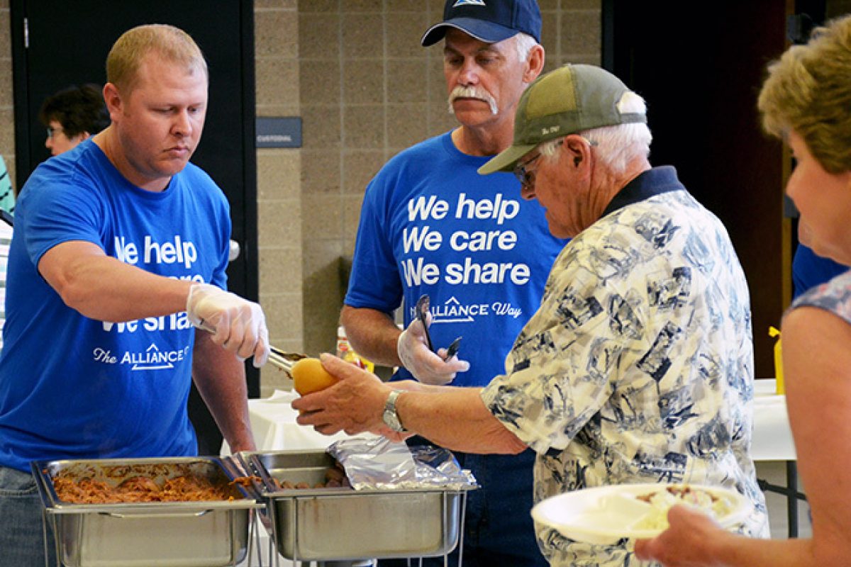 Alliance Communications employees serve food as part of a community service project.