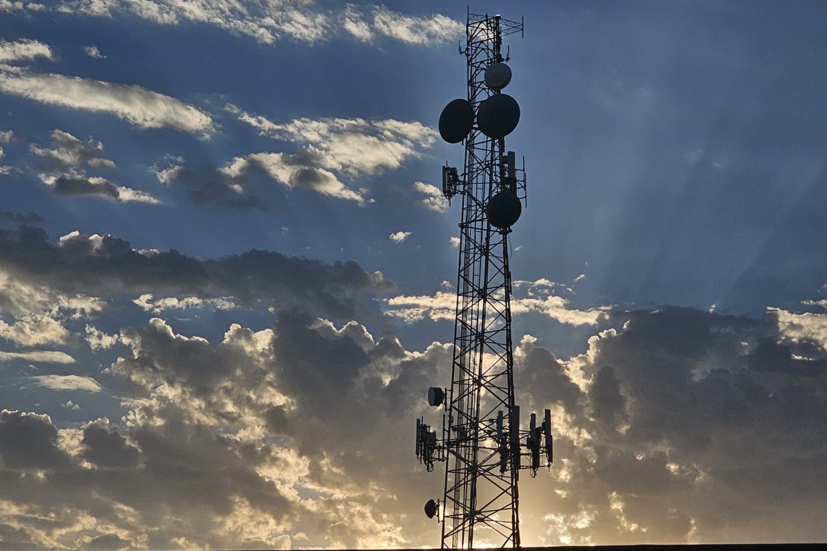 A cell phone tower is shown as the sun sets
