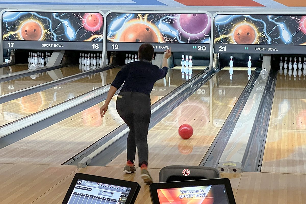 employee rolling a ball down the lane at the bowling alley party