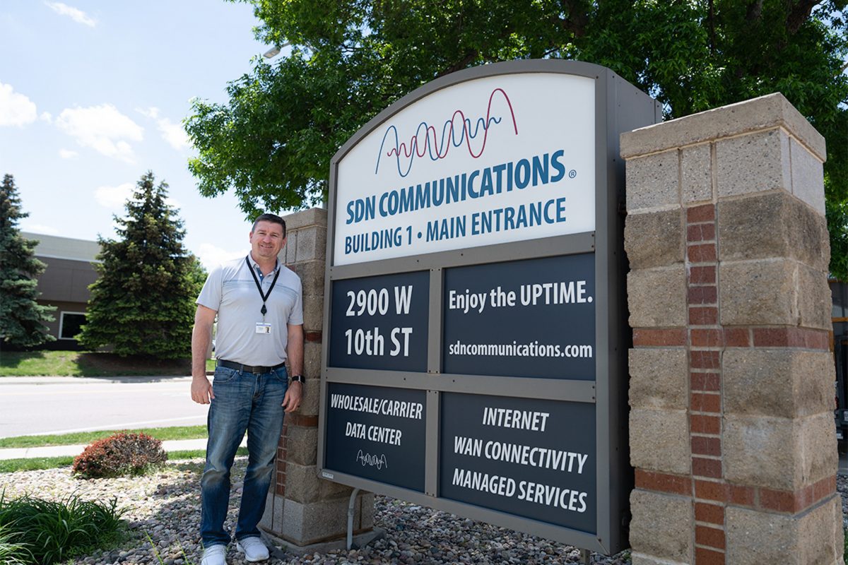 Trevor Lawhorn stands near front signage of a building