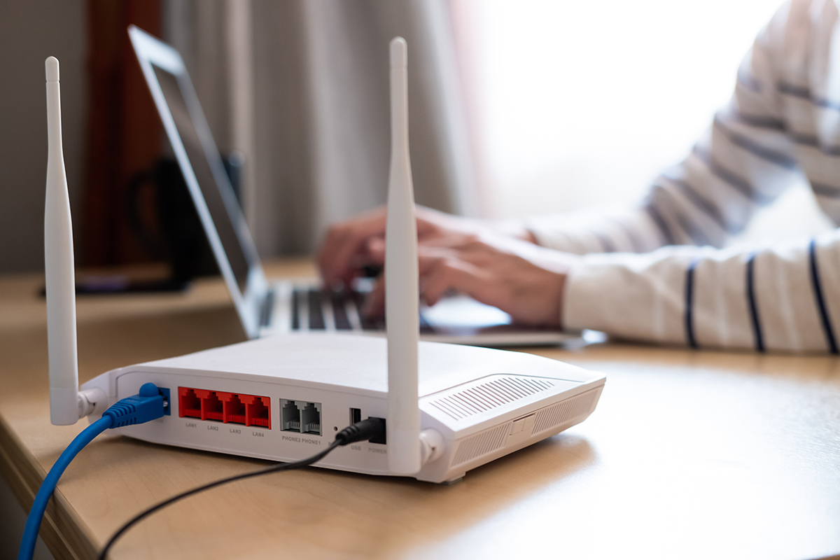 wi-fi router on desk while person works from home on laptop