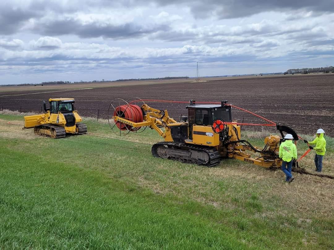 Crews plowing fiber into easement along a field in rural South Dakota