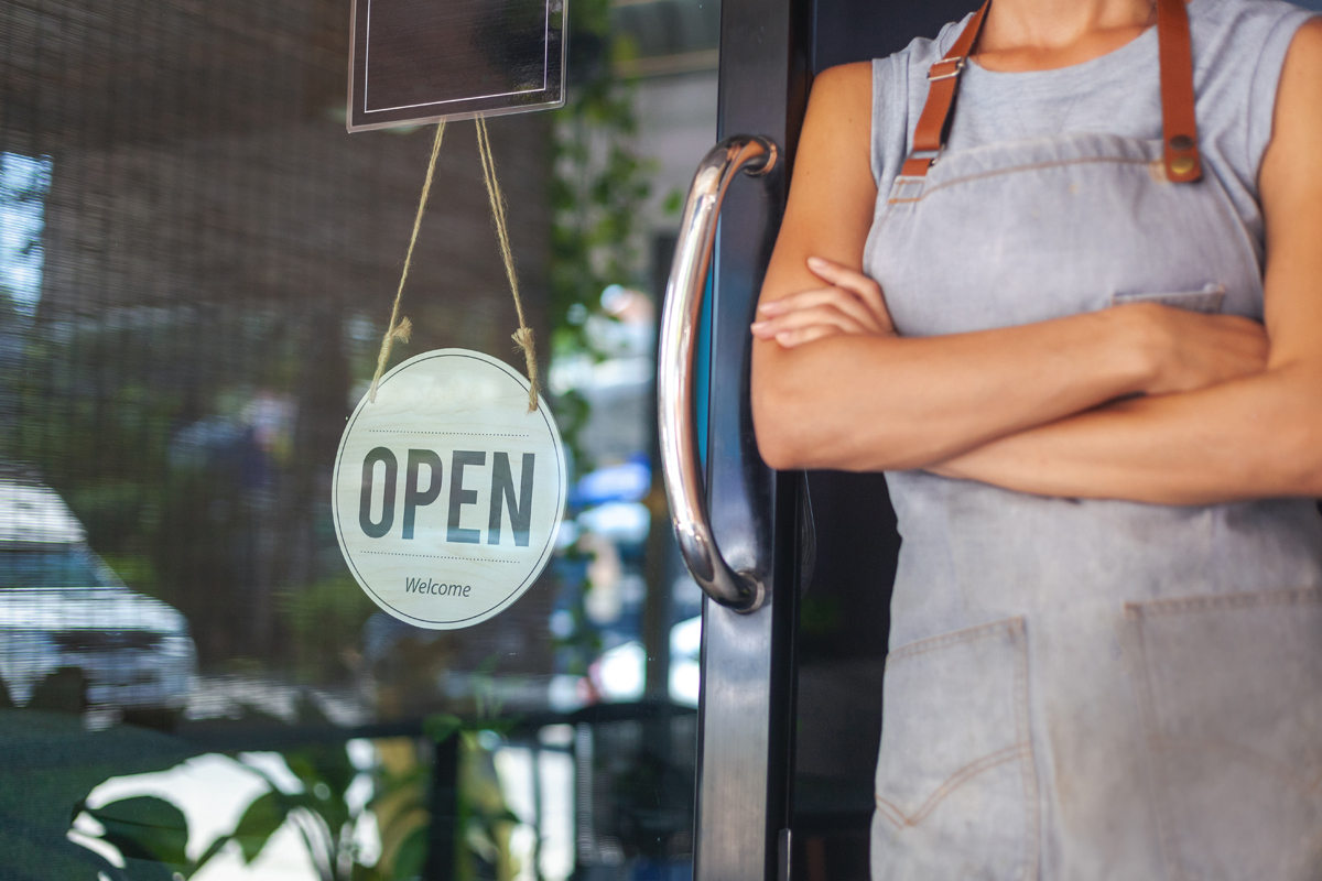 Business owner standing at door with open sign